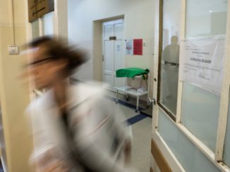 A képen egy kórházi ápoló látható, aki siet elhagyni a kórtermet.
